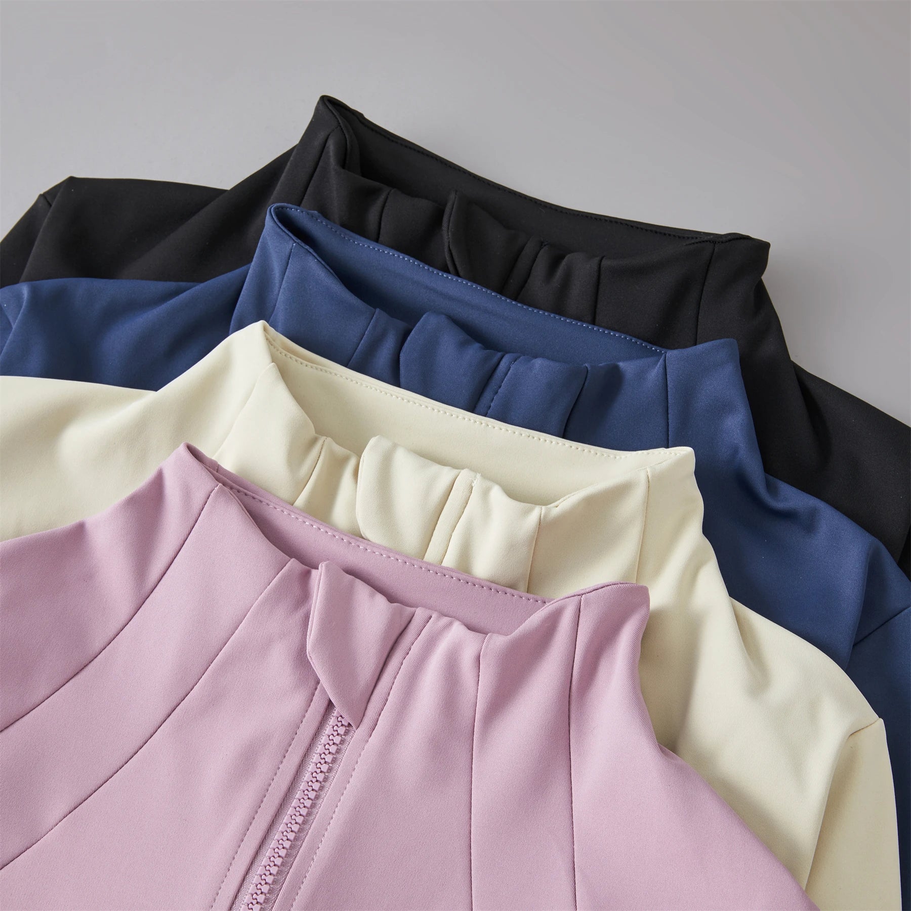 Close-up of a sleeveless top in various colors including black, blue, beige, and pink.