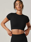 Woman wearing a black crop top against a plain background