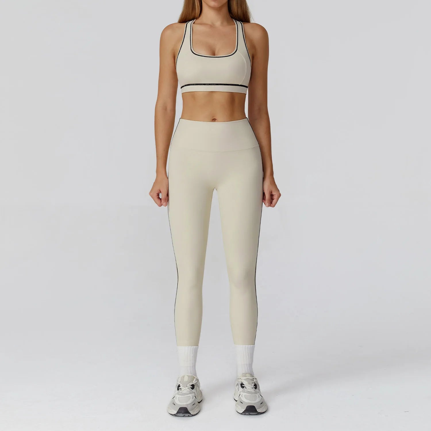 Person wearing a beige sports bra and leggings set on a white background