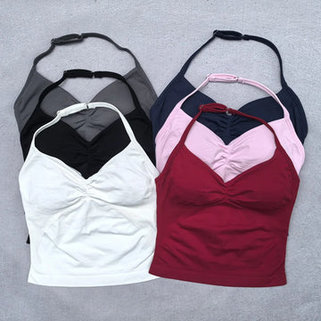 Four tank tops in black, white, pink, and red on a gray background