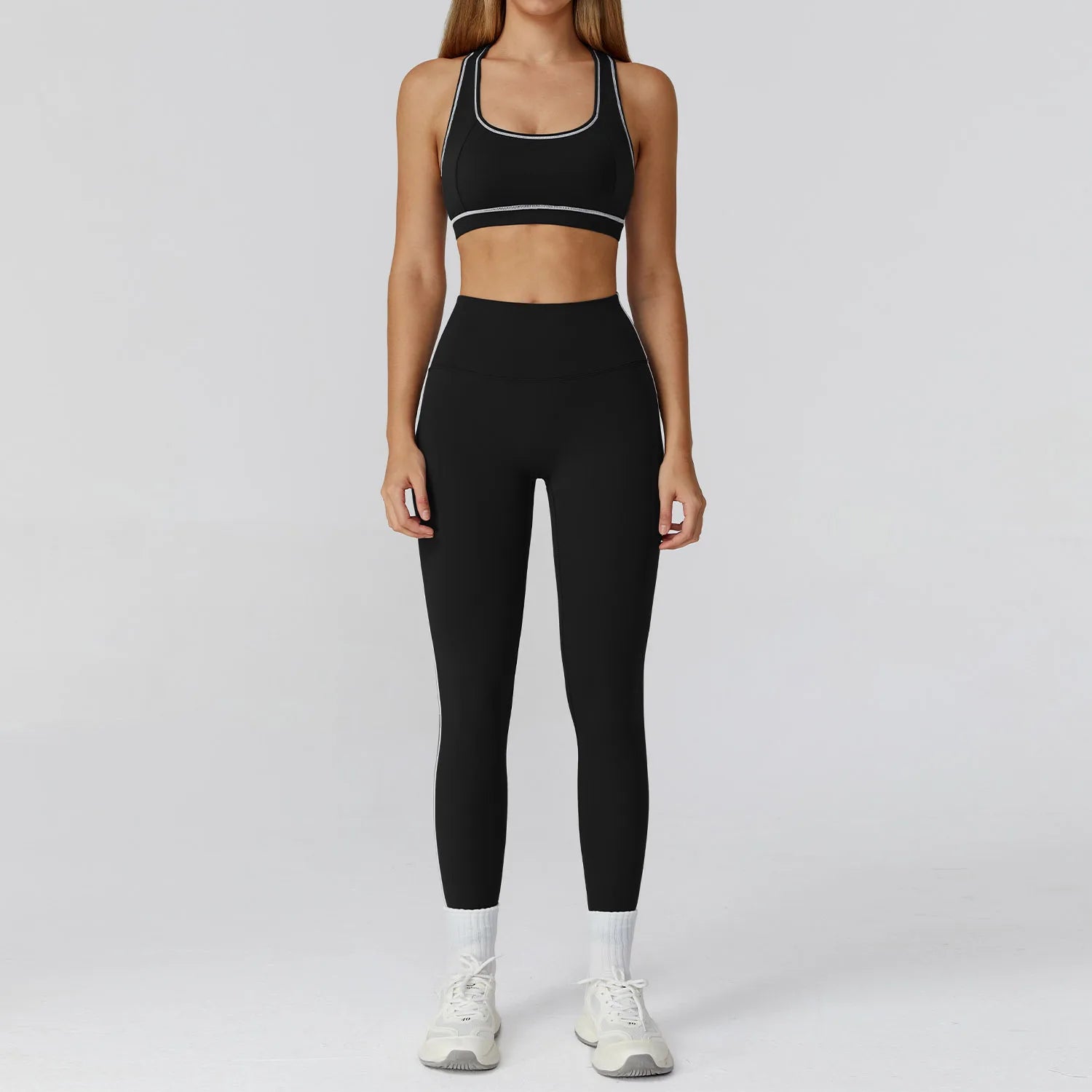 Person wearing a black sports bra and leggings set on a light gray background